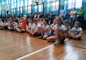 Uczniowie siedzą w sali gimnastycznej